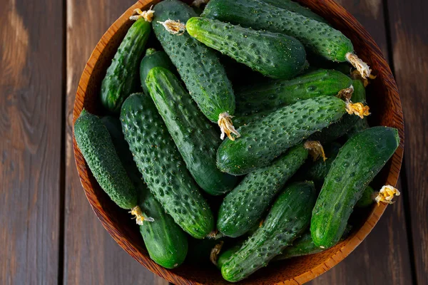 Los pepinos en la escudilla sobre la superficie de madera — Foto de Stock