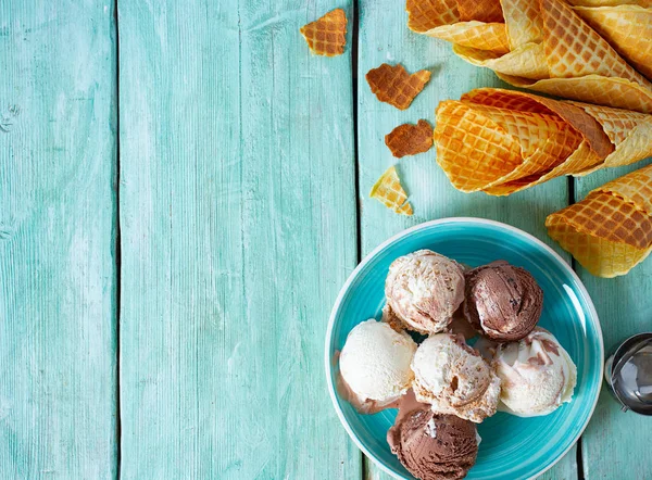 Ice cream and waffle cones on turquoise wooden surface — Stock Photo, Image