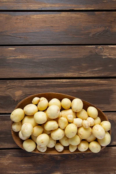 Nieuwe aardappelen op een bruin houten oppervlak — Stockfoto