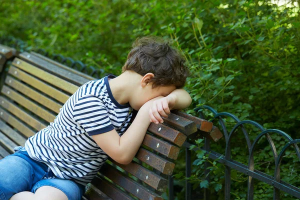 孤独な少年が3月に公園に座っています — ストック写真