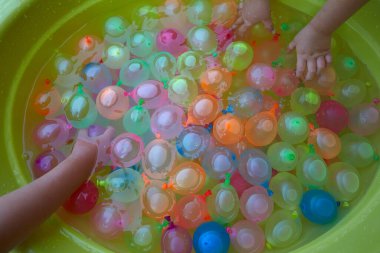 Plastik bir havuzda bir sürü renkli su balonu.