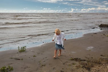 Boş dalgalı bir sahilde tatlı bir kız.