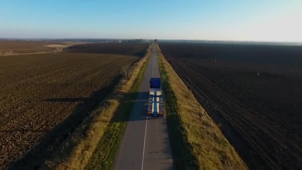 Latające wysoko nad ciężarówki naczepy towarowe przewożące towary na ruchliwej autostradzie całym kraju w piękne letnie wieczory. Ruchu, jazdy i prędkości na autostradzie zajęty w golden sunset — Wideo stockowe