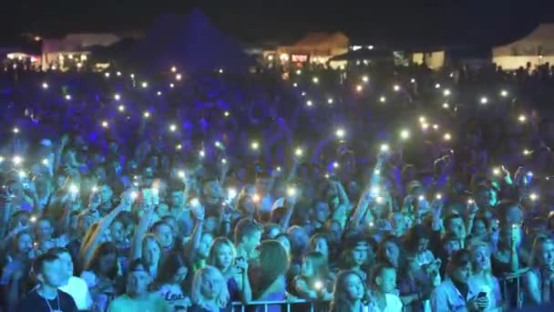 Syuting lambat dari orang-orang di konser melambaikan tangan dengan ratusan sel menciptakan kesatuan cahaya — Stok Video