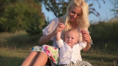 Güzel genç bir anne ile küçük oğlu gölün çevresinde güneşli bir günde yürümek.