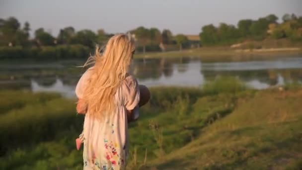 Caminhe ao redor do lago de uma bela jovem mãe com seu filho em um dia ensolarado . — Vídeo de Stock