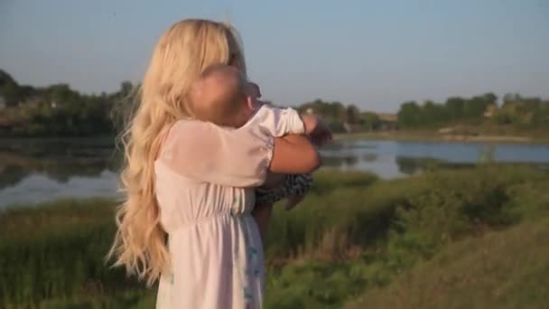 Spaziergang um den See einer schönen jungen Mutter mit ihrem kleinen Sohn an einem sonnigen Tag. — Stockvideo