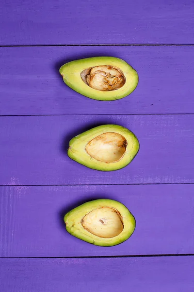 Gesneden Groene Avocado Een Paarse Houten Achtergrond — Stockfoto