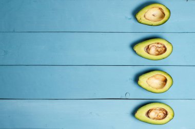 Mavi arkaplanda avokado yarıları