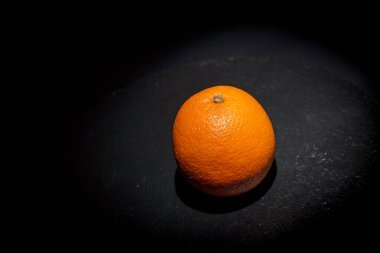 Siyah arka plan ve siyah yüzey üzerinde olgun turuncu