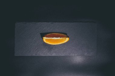 Siyah arkaplan ve siyah yüzey üzerinde olgun turuncu ve turuncu dilimler