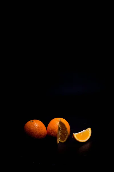 Ripe orange on a black background and black surface