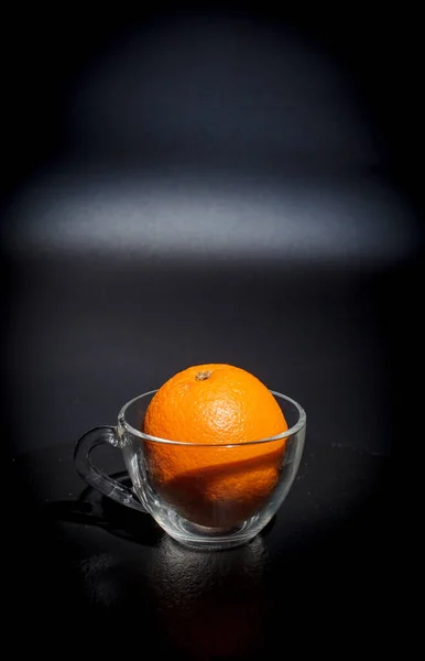 Ripe orange on a black background and black surface