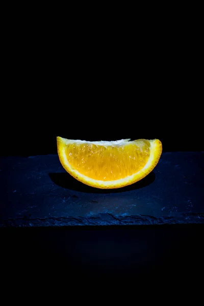 Ripe orange and orange slices on a black background and black surface
