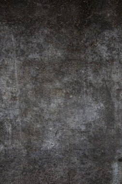 Çizik ve çatlaklarla kaplı eski, koyu beton duvar dokusu..