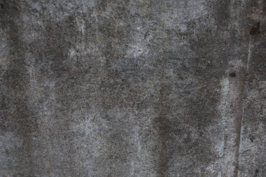 Çizik ve çatlaklarla kaplı eski, koyu beton duvar dokusu..