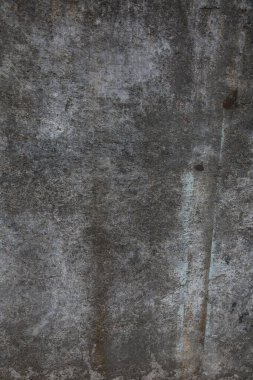 Çizik ve çatlaklarla kaplı eski, koyu beton duvar dokusu..
