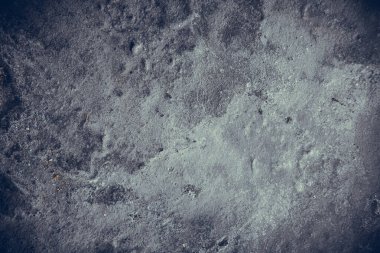 Çizik ve çatlaklarla kaplı eski, koyu beton duvar dokusu..