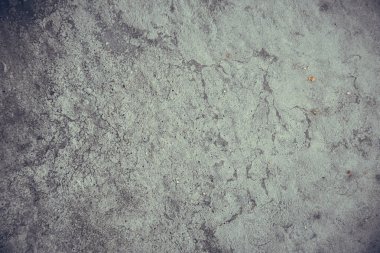 Çizik ve çatlaklarla kaplı eski, koyu beton duvar dokusu..