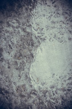 Çizik ve çatlaklarla kaplı eski, koyu beton duvar dokusu..