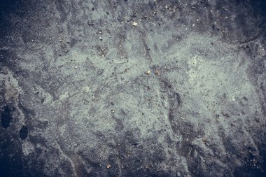 Çizik ve çatlaklarla kaplı eski, koyu beton duvar dokusu..