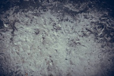 Çizik ve çatlaklarla kaplı eski, koyu beton duvar dokusu..