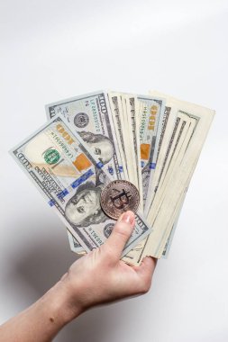 Bir kızın elinde Bitcoin para ve beyaz bir arka planda dolar