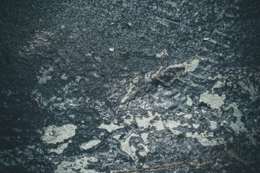 Çizik ve çatlaklarla kaplı siyah reçine duvar dokusu.