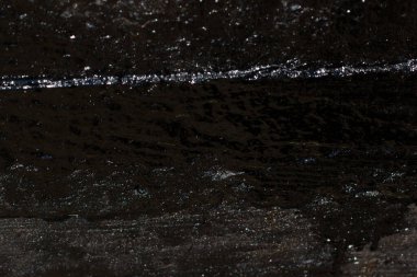 Çizik ve çatlaklarla kaplı siyah reçine duvar dokusu.
