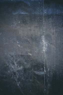 Çizik ve çatlaklarla kaplı siyah reçine duvar dokusu.