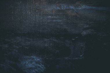 Çizik ve çatlaklarla kaplı siyah reçine duvar dokusu.