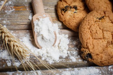 Kuru üzümlü yulaflı zencefilli kurabiye, un ve tahtadan bir yüzey üzerinde buğday.