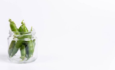 Beyaz bir zemin üzerinde olgun yeşil bezelyeler bir tarlada yetişiyor.