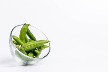 Beyaz bir zemin üzerinde olgun yeşil bezelyeler bir tarlada yetişiyor.