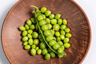 Çiftlikte toplandıktan sonra beyaz bir zemin üzerinde olgun yeşil bezelyeler.