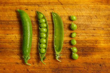 Ahşap bir yüzeyde pişirmek için olgun yeşil bezelyeler.