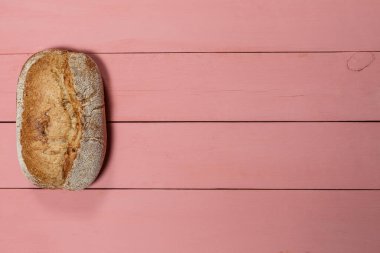 Pembe arka planda taze bir somun glütensiz ekmek.