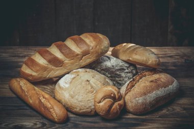 Farklı somun ekmeği un ve glütensiz buğdayla ahşap bir masada pişirilir.