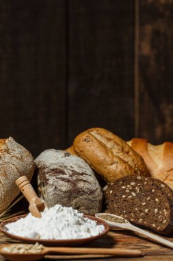 Farklı somun ekmeği un ve glütensiz buğdayla ahşap bir masada pişirilir.