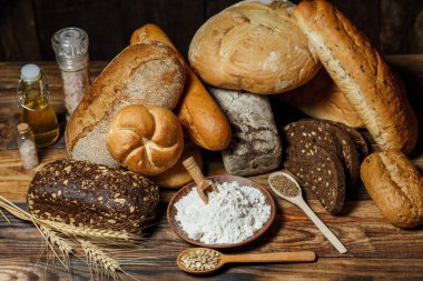 Farklı somun ekmeği un ve glütensiz buğdayla ahşap bir masada pişirilir.