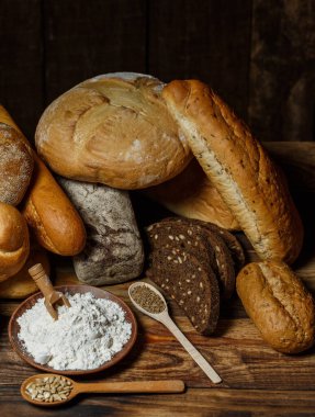 Farklı somun ekmeği un ve glütensiz buğdayla ahşap bir masada pişirilir.