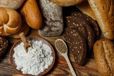 Farklı somun ekmeği un ve glütensiz buğdayla ahşap bir masada pişirilir.