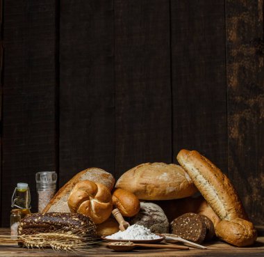Farklı somun ekmeği un ve glütensiz buğdayla ahşap bir masada pişirilir.