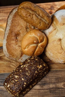 Farklı somun ekmeği un ve glütensiz buğdayla ahşap bir masada pişirilir.