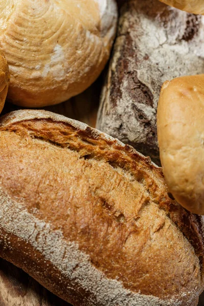 Farklı somun ekmeği un ve glütensiz buğdayla ahşap bir masada pişirilir.