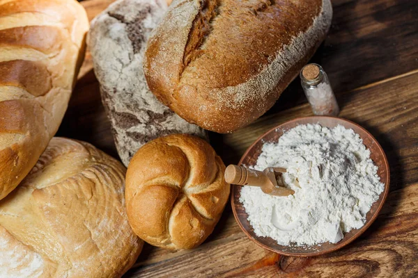 Farklı somun ekmeği un ve glütensiz buğdayla ahşap bir masada pişirilir.