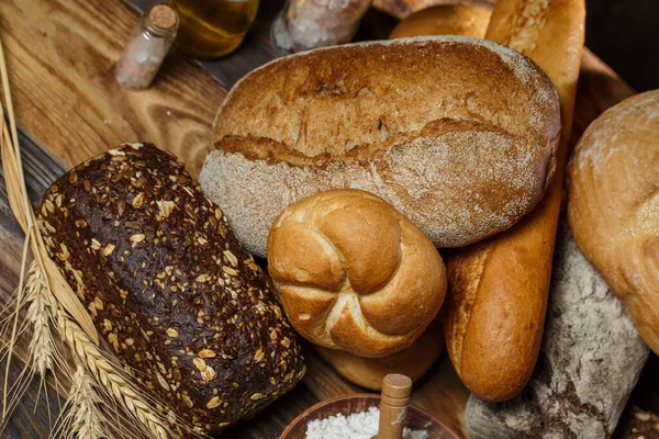 Farklı somun ekmeği un ve glütensiz buğdayla ahşap bir masada pişirilir.