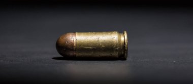 9mm 'lik tabanca mermisi ve siyah arka planda nefsi müdafaa.