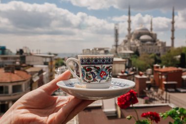 İstanbul 'daki cami manzaralı, elinde süslerle geleneksel Türk çay fincanı