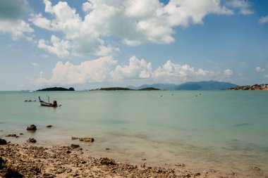Tayland 'da mavi okyanuslu, beyaz kumlu ve tipik balıkçı tekneli tropik bir sahil.